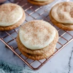 Frosted snickerdoodle cookies with cinnamon sugar topping on a plate