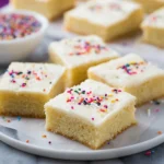 Delicious homemade sugar cookie bars on a plate, topped with colorful sprinkles.